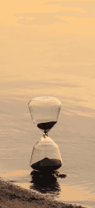 Reloj de arena sobre el mar, con el reflejo del atardecer.